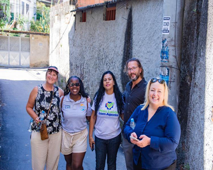 Três mulheres e um homem estão abraçados e olham para a câmera. E sorriem