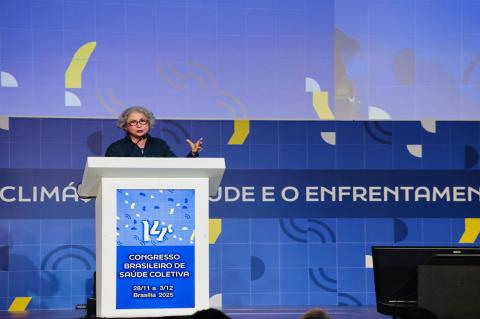 Mulher de óculos e cabels grisalhos fala em um púlpito onde se lê 14º Abrascão