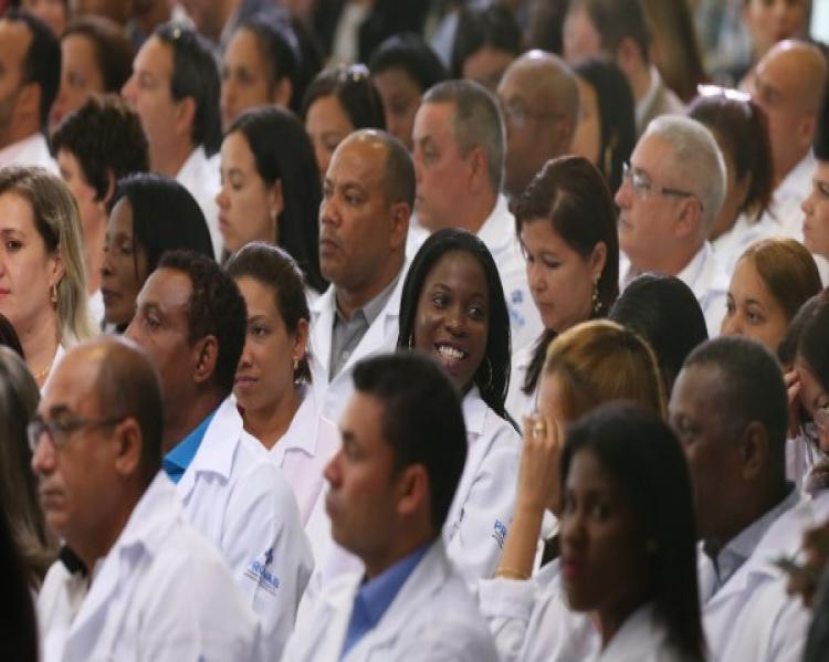 Homens e mulheres de jaleco branco sentados em um auditório