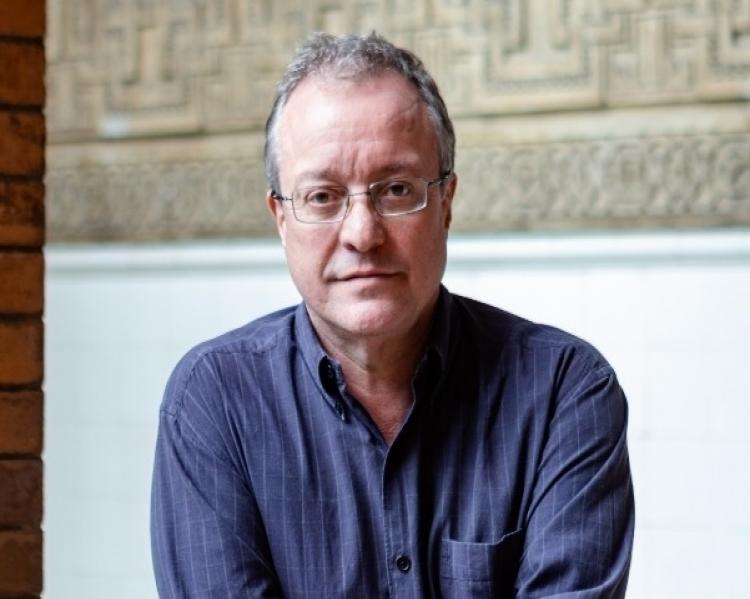 Homem de camisa social azul e óculos em primeiro plano