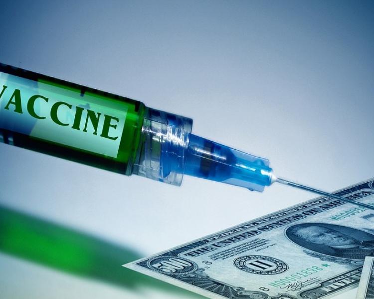 Seringa, onde se lê a palava 'vaccine' ligeiramente cortada,com a agulha apontadapara uma nota de dólar