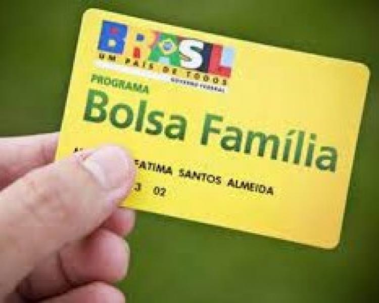 Mão segurando um cartão amarelo onde se lê Bolsa Família