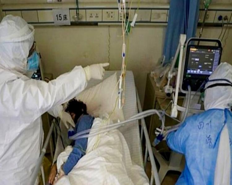 Profissionais de saúde com equipamentos de proteção observam paciente monitorizado em leito de UTI