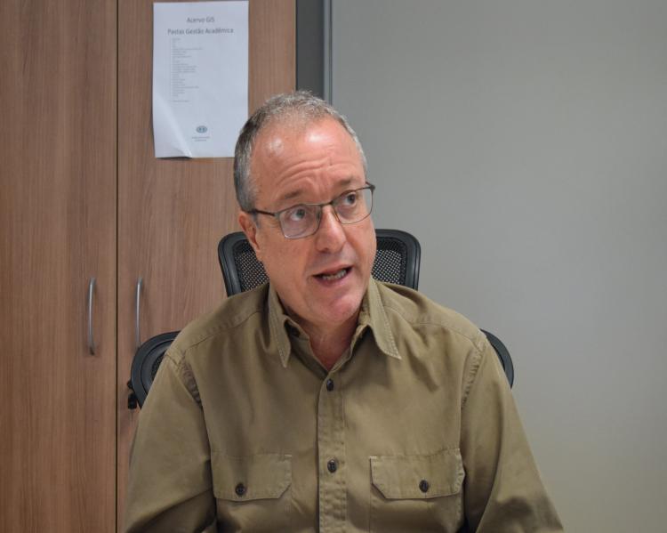 Homem de óculos e camisa marrom, em momento de fala