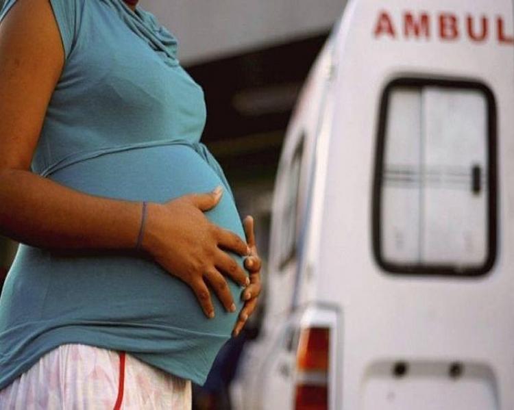 Mulher, da qual não se vê o rosto, com as mãos sobre a barriga grávida