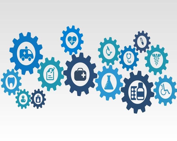 Várias engrenagens desenhadas em tons de azul, trazendo no centro de cada uma imagens relacionadas ao cuidado à saúde, como tubos de ensaio, seringas, ambulância, microscópio