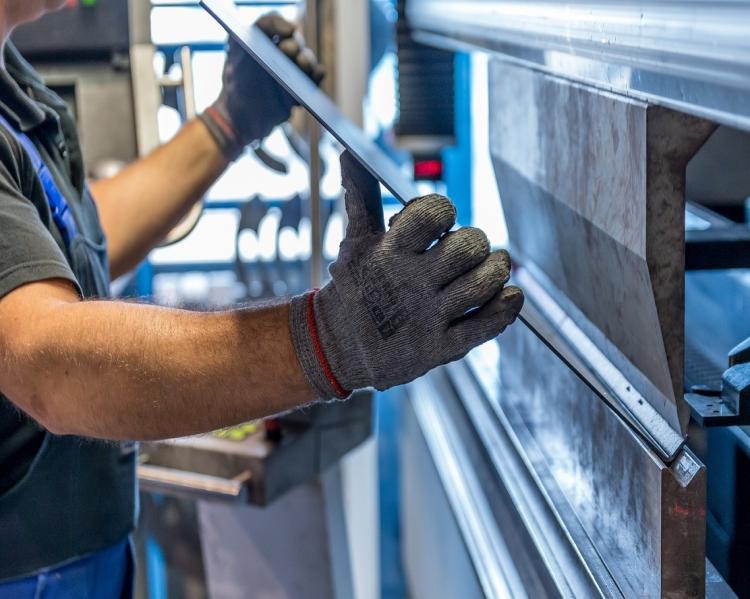 Mãos de operário com luvas seguram uma placa