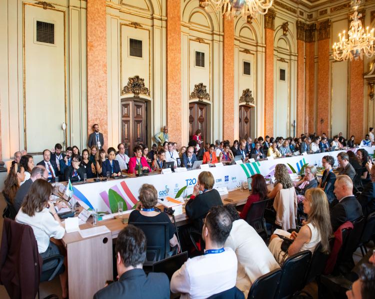 Dezenas de homens e mulheres sentados em torno de uma enorme mesa