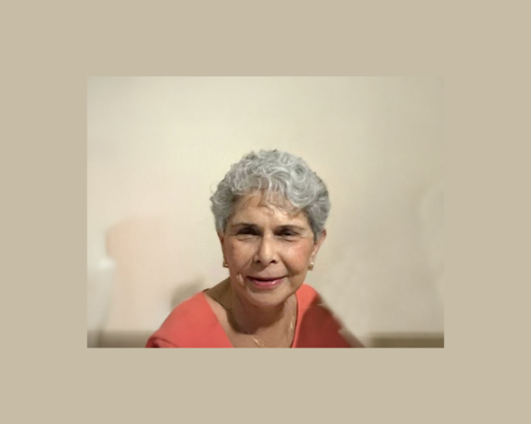 Mulher de cabelos curtos, grisalhos sorri bem de perto para a foto