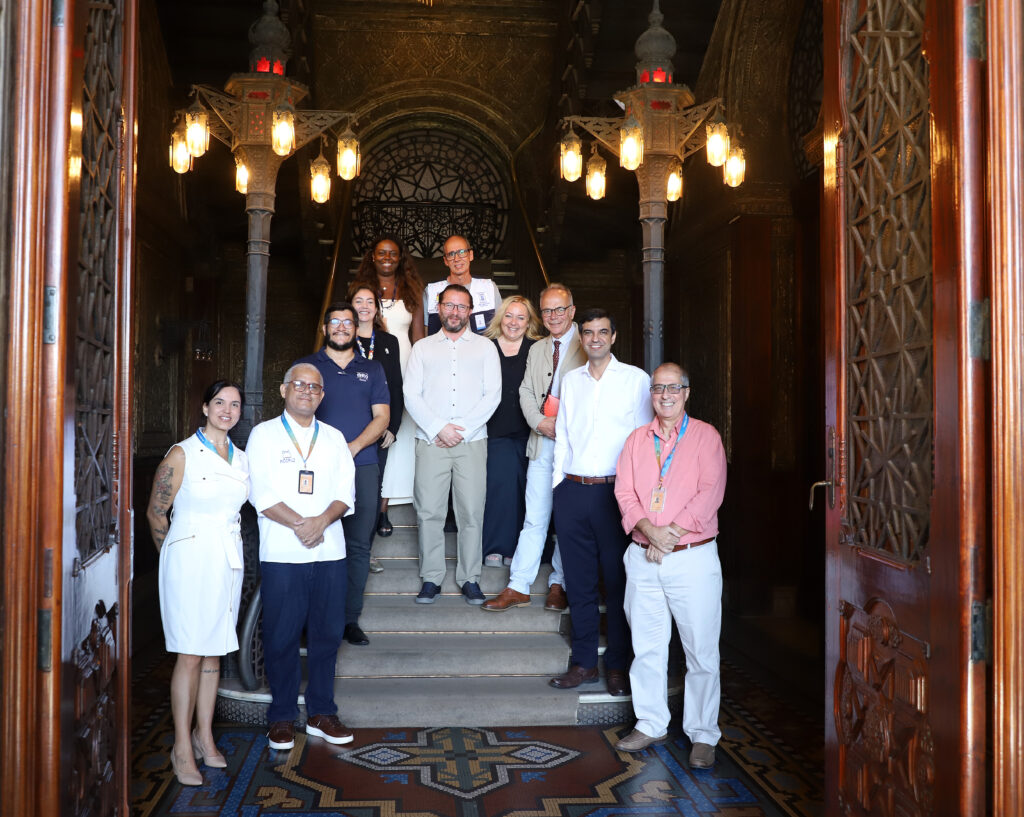 Homens e mulheres estão de pé lado a lado nos degraus de uma escadaria dentro do Castelo Mourisco da Fiocruz